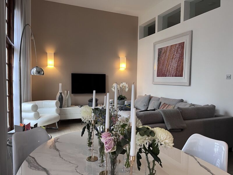 Bright living room with taupe walls, a large painting and a grey corner sofa