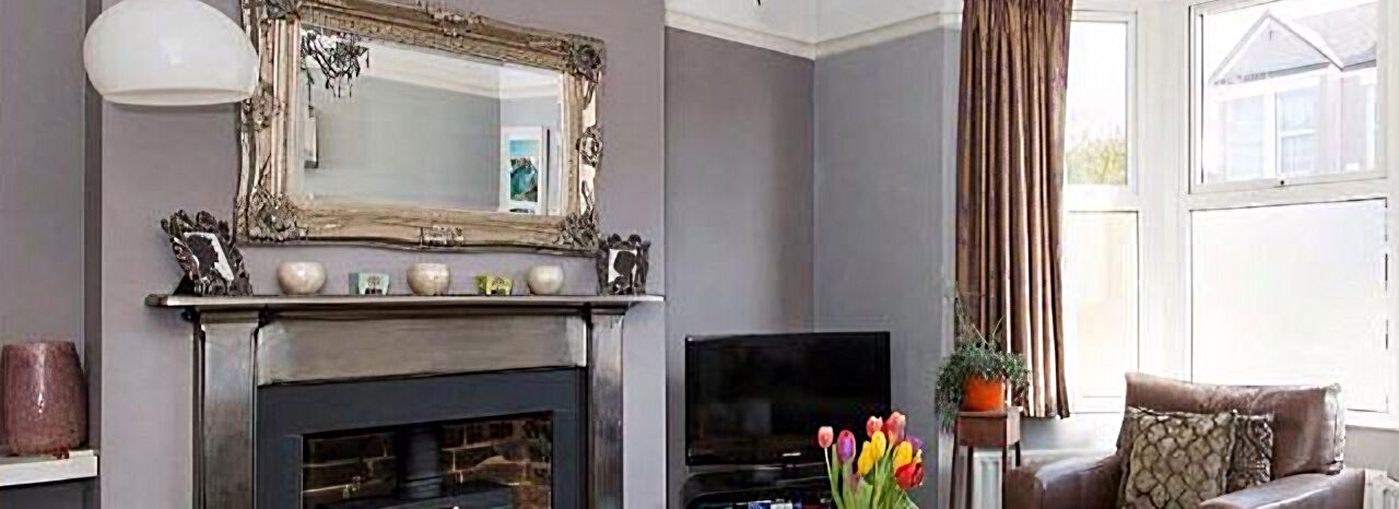 Living room with lilac-grey walls, a wood burner and a large mirror